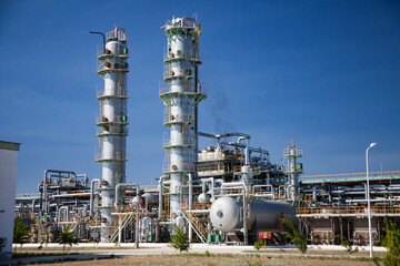 Panorama of petrochemical plant. Distillation towers, pipes and pipelines, heat exchangers and equipment of oil refinery. Blue sky background. Wide-angle.
