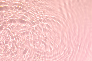 De-focused. Closeup of pink transparent clear calm water surface texture with splashes and bubbles. Trendy abstract summer nature background. Coral colored waves in sunlight.