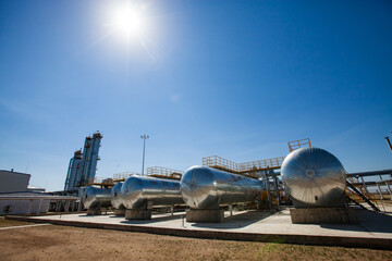 Oil refinery and gas processing plant in desert. A few heat exchangers and distillation towers (refinery columns) on blue sky with sun.
