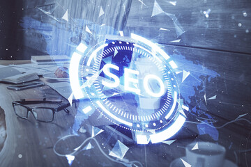 Multi exposure of table with computer and seo drawing hologram. Search optimization concept.