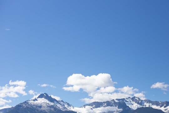 Snowy mountains with clouds against blue sky