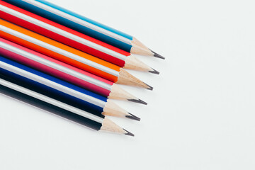 Multicolored wooden graphite pencils on light background. Top view.