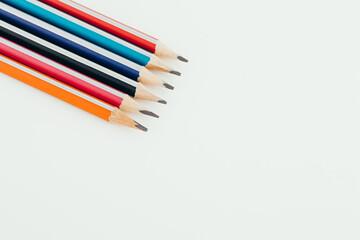 Multicolored wooden graphite pencils on light background. Top view.