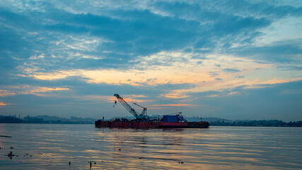 A ship with crane on Mahakam River, Samarinda in the morning. 