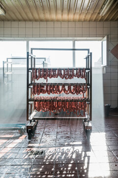 Raw sausages hanging on mobile rack in a butcher shop