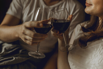 Man and woman clanging wine glasses of wine at the bad 
