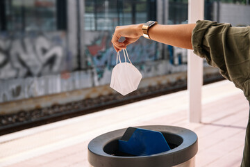 Woman dumping mask into bin on station
