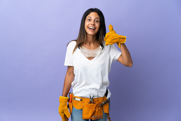 Young electrician woman isolated on purple background making phone gesture. Call me back sign