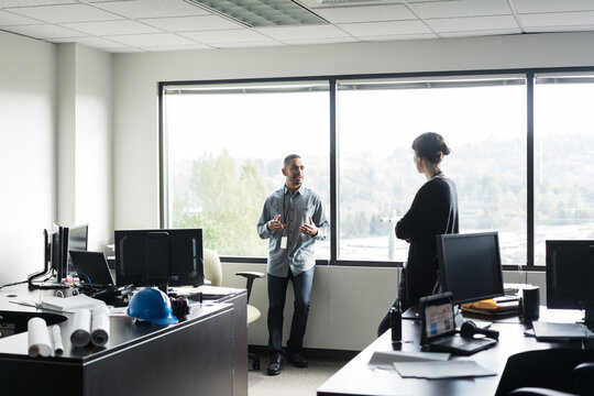Two office workers talking in a brightly lit room
