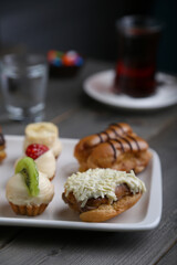 Eclairs and mini tarts on a white plate and tea