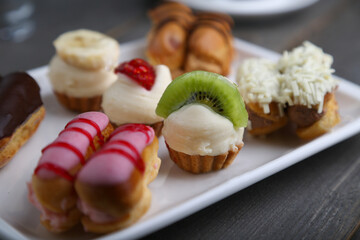 Eclairs and mini tarts on a white plate