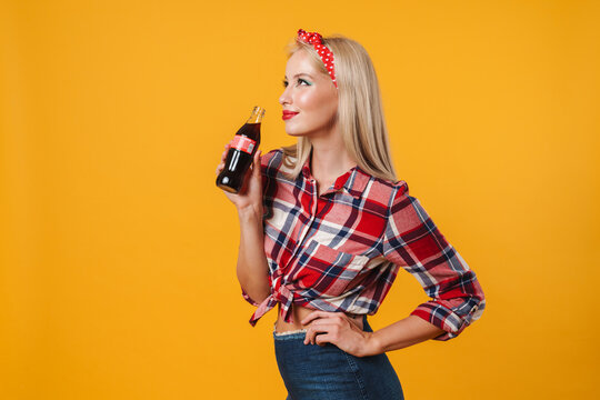 Image of happy charming pinup girl posing with soda and smiling