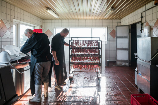 Two young butchers mincing meat for fresh sausages