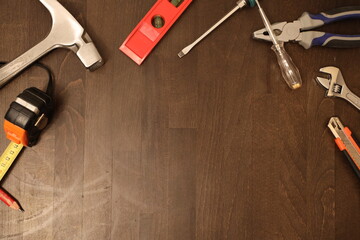 Tischlerwerkzeug auf einem Holztisch. Zu sehen ist ein Ma&szlig;band, ein Bleistift, Hammer, Kombizange, Wasserwage und Schraubenzieher.