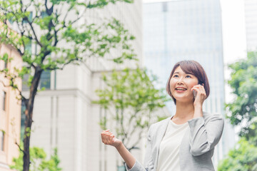 Fototapeta premium オフィス街で電話をする若い女性
