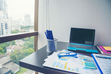 Office laptop business financial document chart and graph on wooden table with coffee cup. Flat lay notebook computer laptop on office desk. No people business graph chart mockup on business workspace