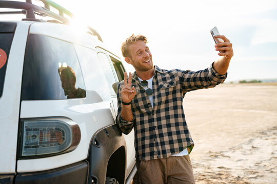 Attractive young man leaning on a car while standing