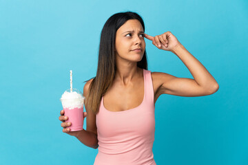 Young woman with strawberry milkshake having doubts and thinking