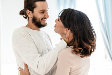 Image of romantic joyful couple smiling and hugging while standing