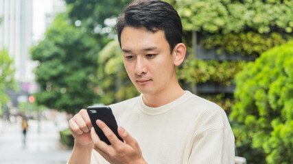 オフィス街でスマートフォンを操作する若い男性