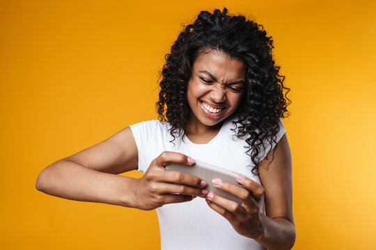 Image of excited african american woman playing video game on cellphone