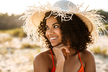 Positive young african woman posing at the beach outside