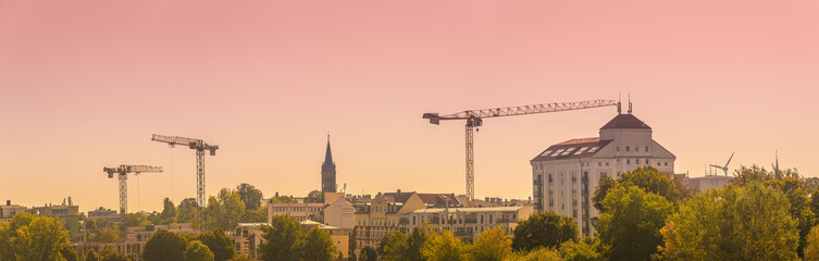 Panoramic view over downtown of Magdeburg with many construction cranes in the horizon during red...