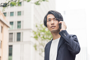 オフィス街で電話をする若い男性