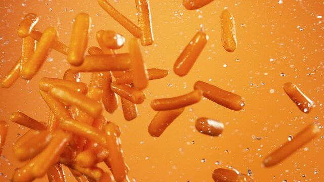 Super slow motion of baby carrots flying up in the air with water splashes. Filmed on high speed cinema camera, 1000 fps.