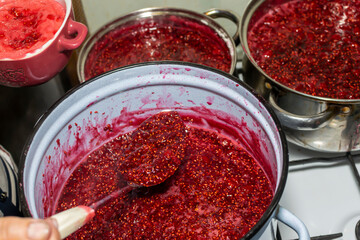 Cooking raspberry jam on a gas stove.