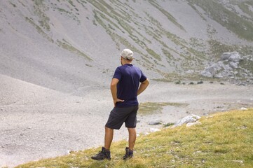 An isolated man observes the mountains from the summit after a day of trekking (Marche, Italy,...