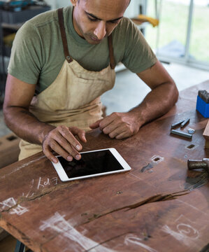 Man Working On IPad In His Workshop