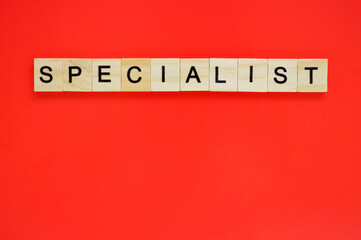 Word specialist. Wooden blocks with lettering on top of red background. Top view of wooden blocks with letters on red surface