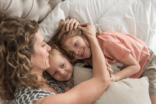 A Family Snuggling Together On A Bed