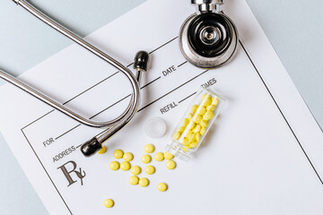 Medical concept. Yellow pills with stethoscope, pills, notepad, medical prescription on the doctor's desktop. Treating a patient in a hospital with medication.