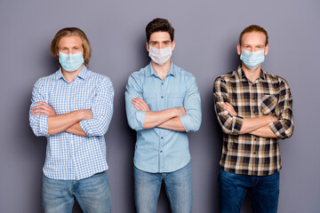 Portrait of three serious masculine guys best buddy fellow corona virus fight team folded arms wear medical mask isolated over gray pastel color background