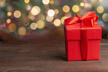 Red gift box with red ribbon,  blurred background with bokeh