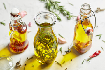 Infused olive oil in glass bottles on white table.
