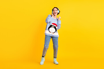 Fototapeta na wymiar Full size photo of pretty youngster attractive lady party newyear listen cool modern technology earphones disco event wear ugly sweater pullover jeans shoes isolated yellow color background