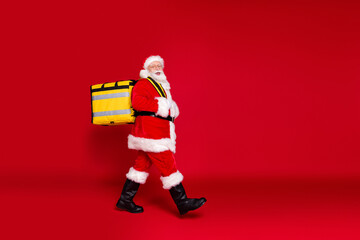 Full length body size profile side view of his he handsome cheery bearded Santa father carrying box festal delivery celebrate newyear isolated bright vivid shine vibrant red color background