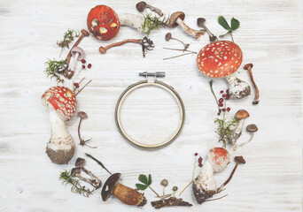 Festive autumn Thanksgiving wreath with mushrooms, fly agaric, moss, red berries, on rustic background. Autumn holiday, Thanksgiving, Halloween concept. Flat lay, top view, copy space