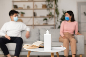 Sanitizer Standing On Desk Separating Asian Couple In Masks Indoor