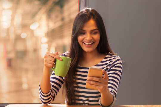 Woman looking at her phone with a coffee mug in her hand	