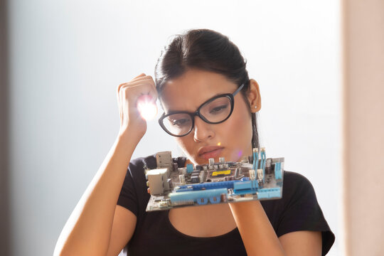 Executive looking at motherboard with a torch in her hand	