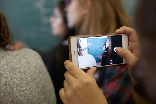 Close up of student taking a photo of the blackboard with a phone