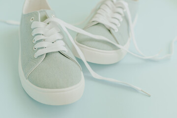 Blue sneakers with white laces on a light blue background. Trendy fashionable casual concept.