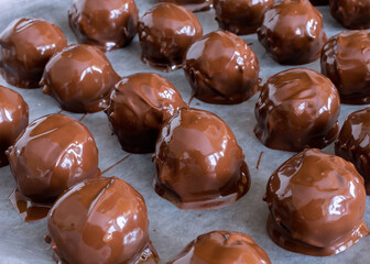 Freshly dipped homemade peanut butter chocolate balls on parchment paper on a cookie sheet.