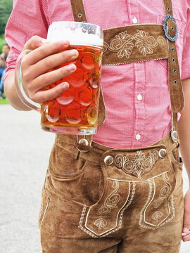 Man holding a glass of beer wearing German Bavarian clothes