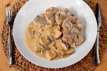 Spicy mushroom sauce with dumplings on white plate.