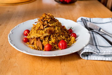 Spicy curry couscous with sliced roasted chicken and cherry tomato on plate.